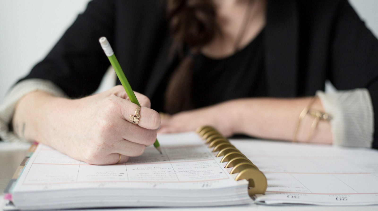 A person writing in a notebook with a pencil