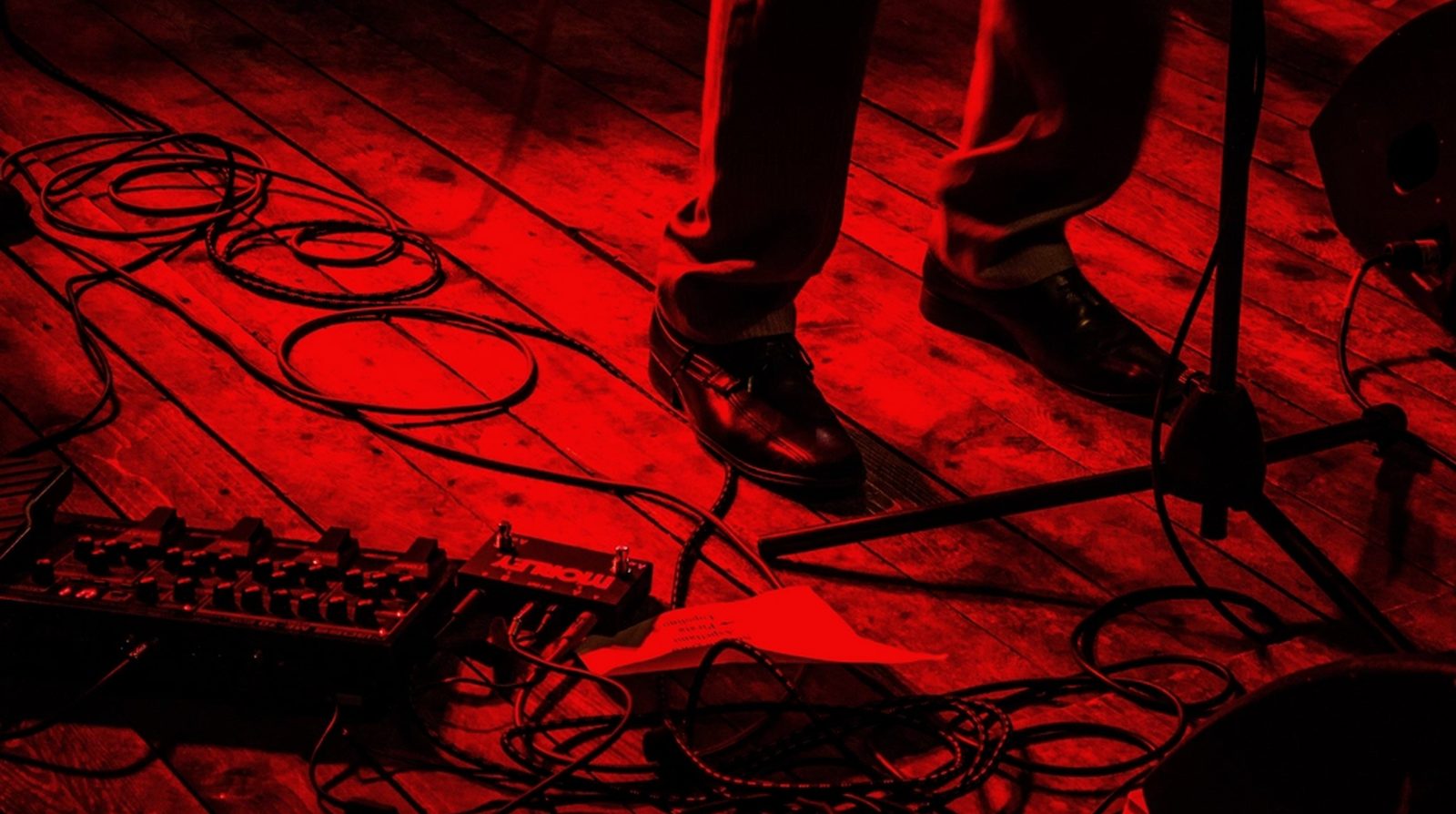 Power and signal cables running across a stage floor under red light, the area to check for leakage before showtime