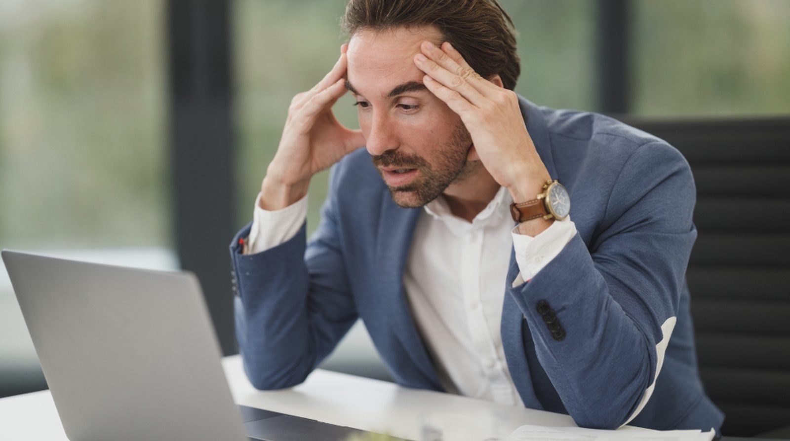 Người đàn ông ôm đầu nhìn màn hình máy tính xách tay với vẻ bế tắc, minh họa cảm giác khi bài viết đã đăng lâu mà vẫn chưa được Google lập chỉ mục