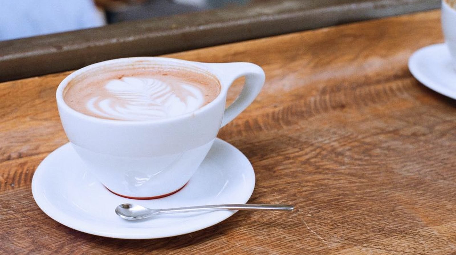 A cup of hot milk coffee on a wooden table in a cafe, illustrating small shops such as cafes testing Zalo advertising on a modest budget