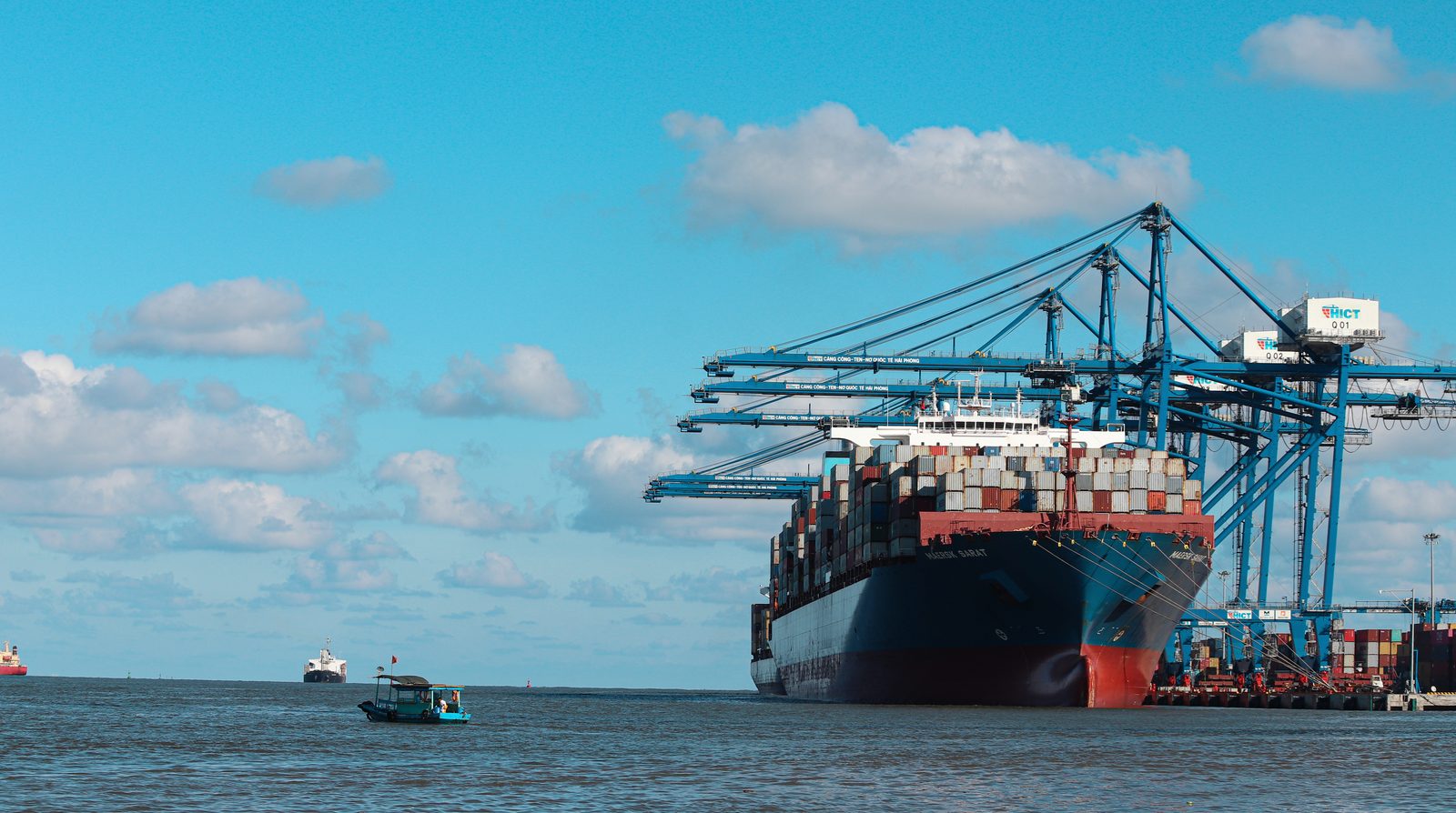 Tàu container cập cảng container quốc tế Hải Phòng, các cần cẩu giàn đang bốc dỡ hàng dưới trời xanh