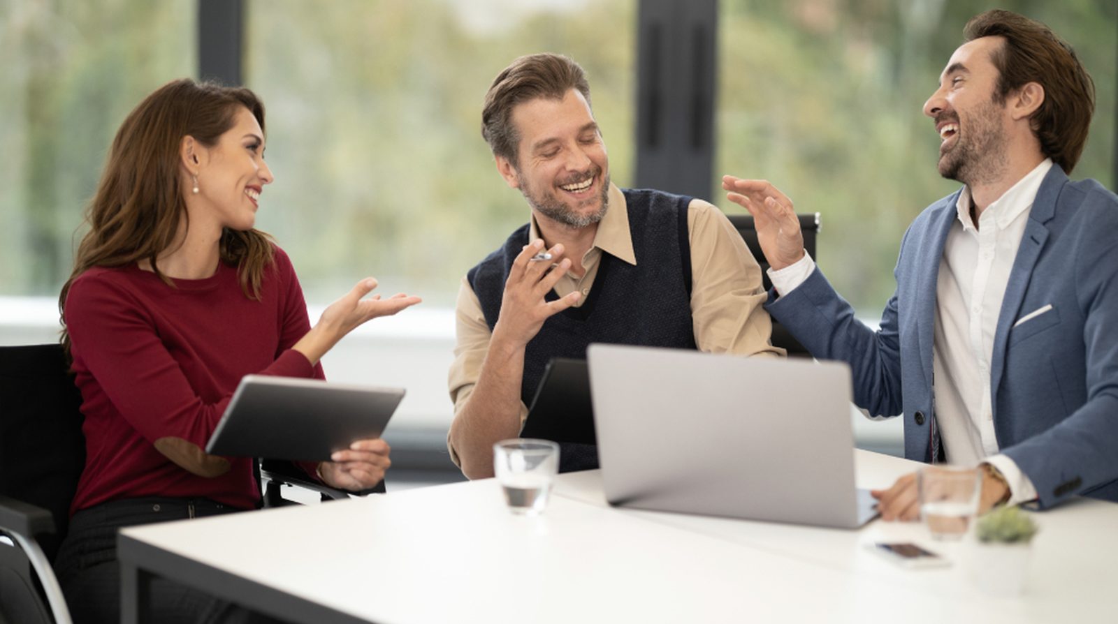 A small marketing team around a table with a laptop and tablet discussing traffic numbers by channel